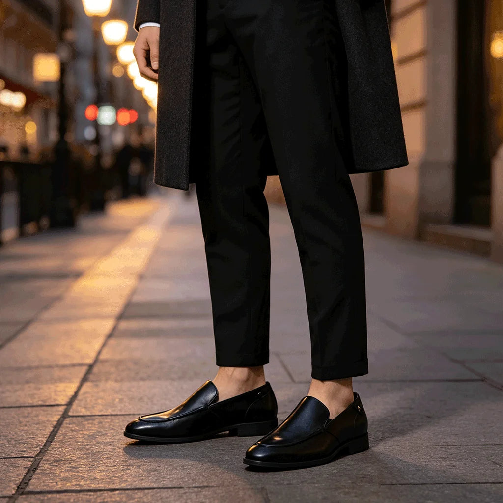 Man standing in black leather loafers on evening city street