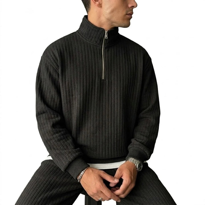 Man wearing black ribbed quarter-zip pullover, side view