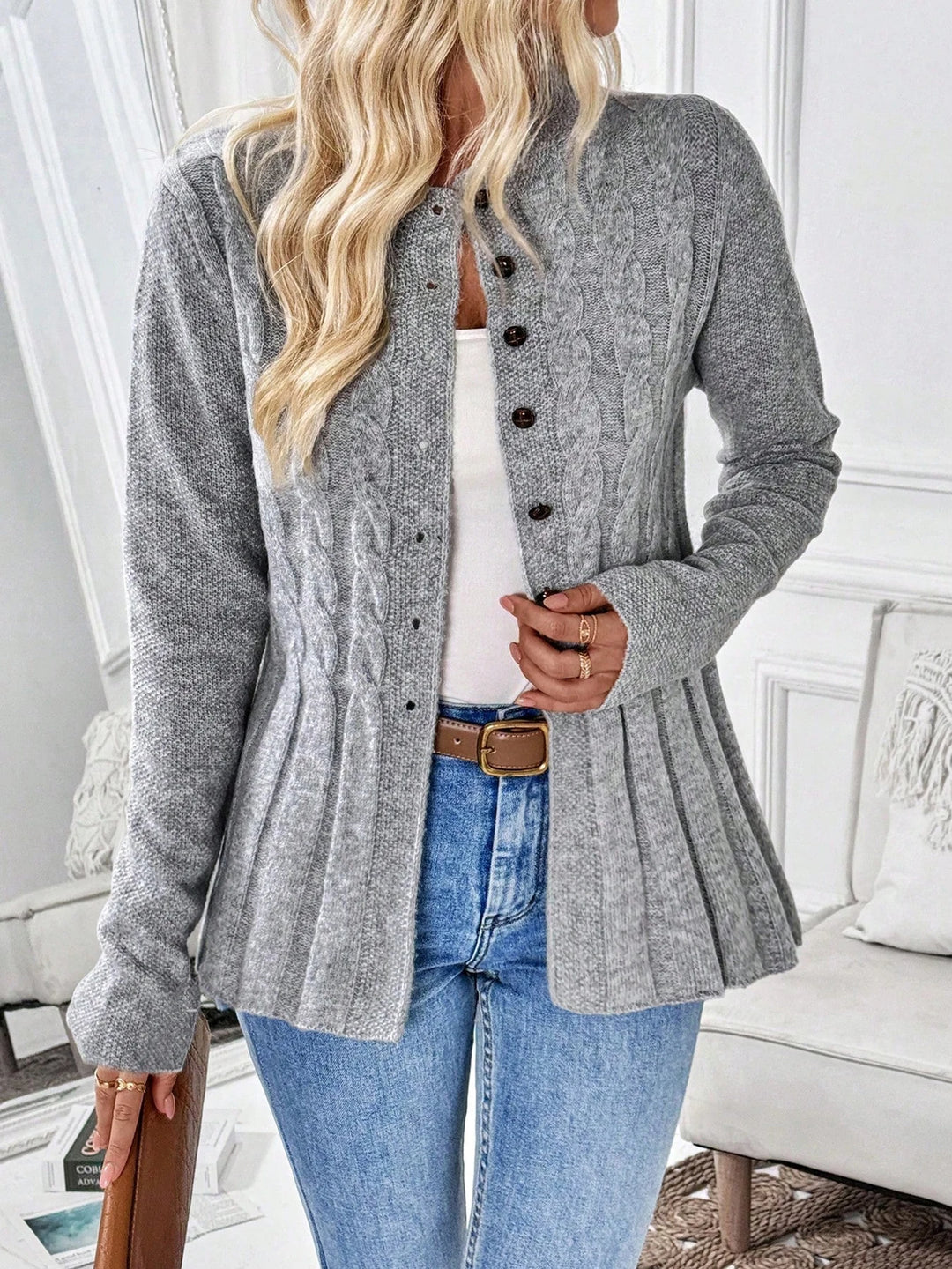 Woman wearing gray cable knit peplum cardigan buttoned partway, front view