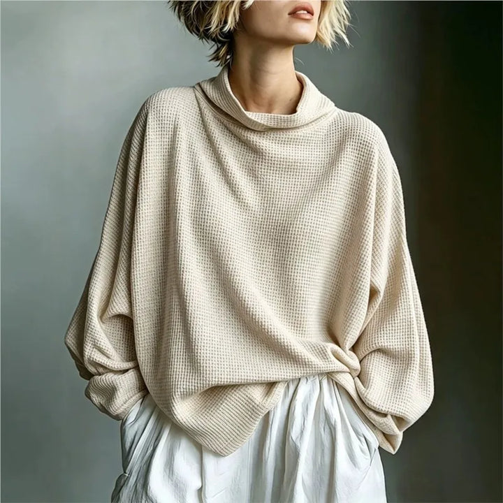 Woman wearing apricot waffle knit top with funnel collar, front view