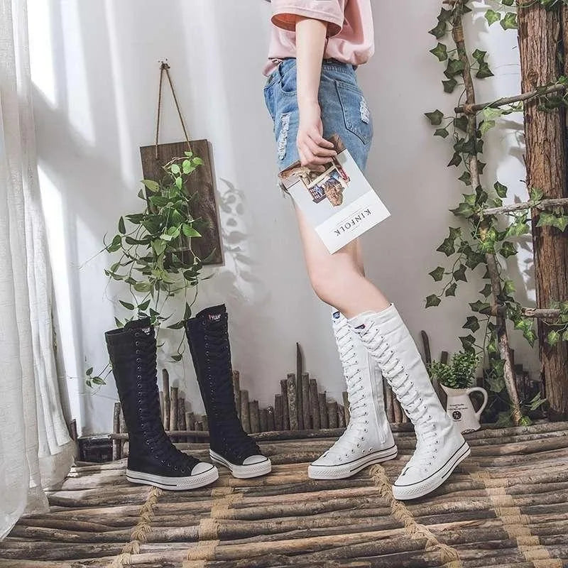 Model standing beside both black and white knee-high lace-up canvas boots