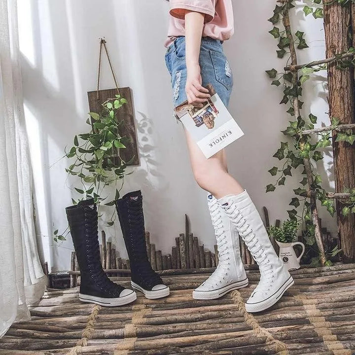 Model standing beside both black and white knee-high lace-up canvas boots
