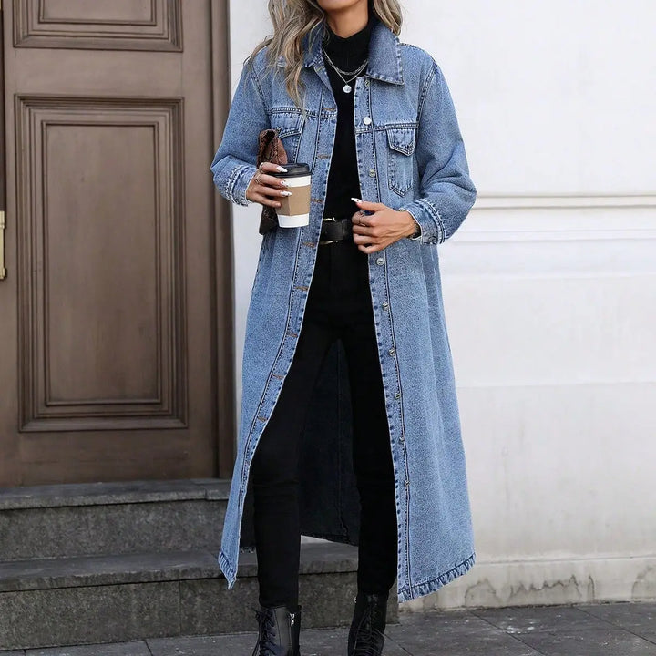 Woman wearing long blue denim coat over black outfit