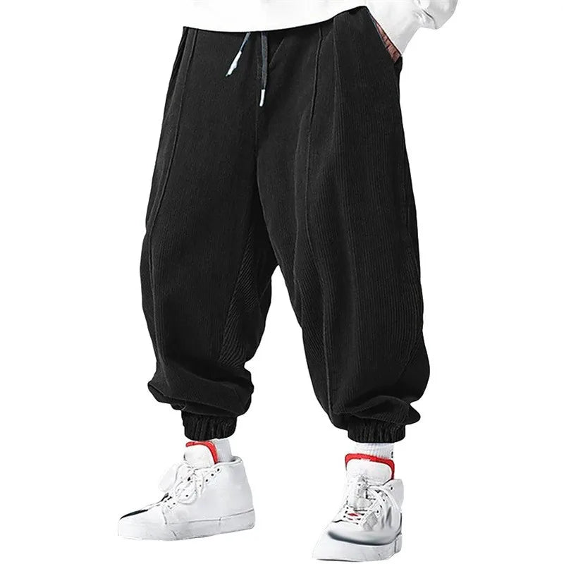 Man wearing black corduroy jogger pants with pleated front