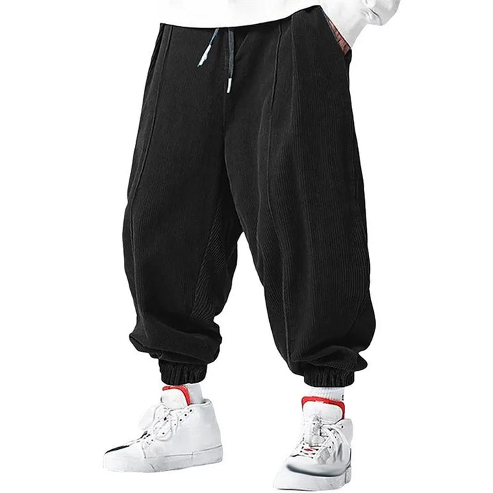 Man wearing black corduroy jogger pants with pleated front