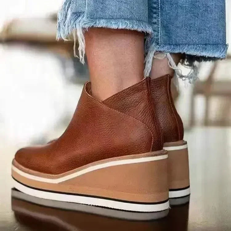 Back view of brown leather wedge ankle boots on model