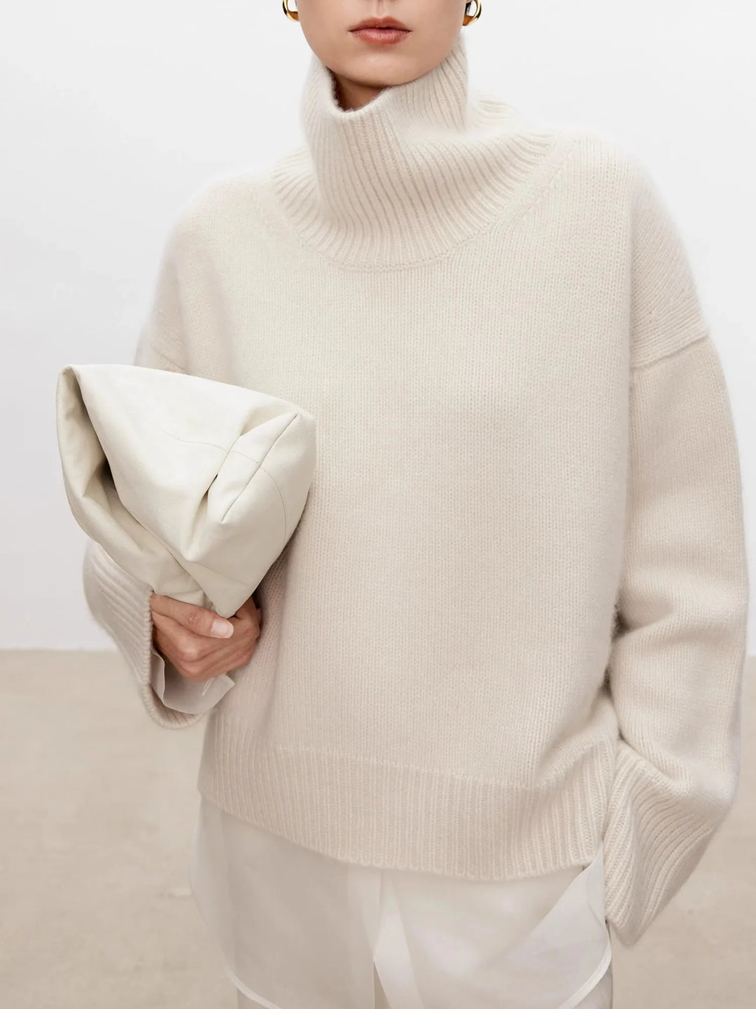 Close-up of ivory cashmere turtleneck sweater with leather clutch