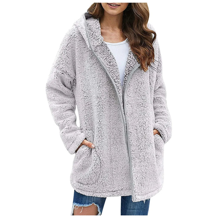 Woman wearing light gray sherpa hooded jacket with hands in pockets