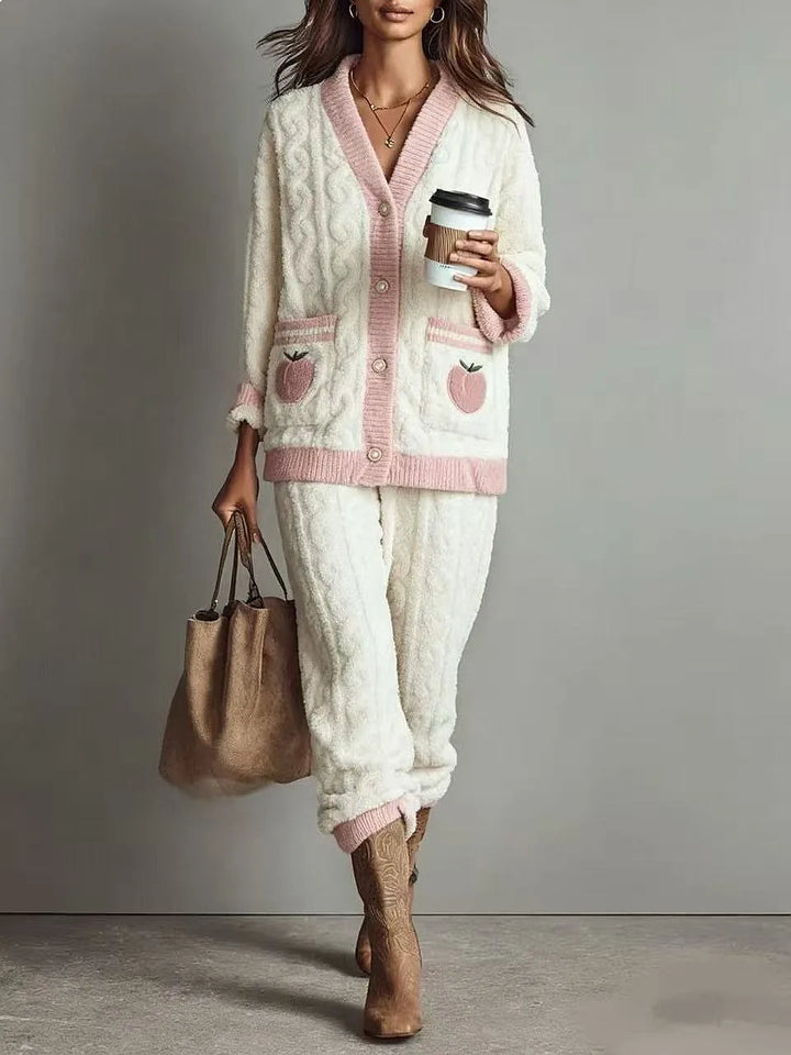 Close-up of white cable knit cardigan with pink trim and fruit embroidered pocket