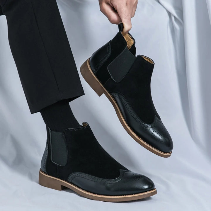 Man wearing black wingtip Chelsea boots