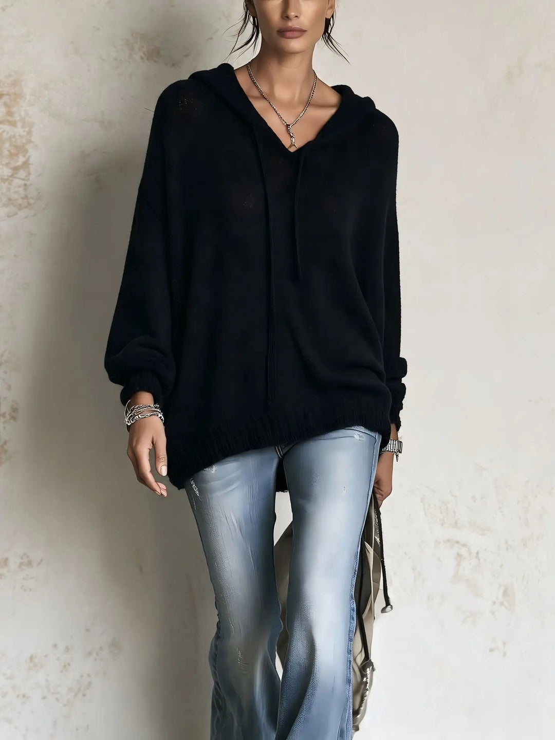 Woman wearing black hooded knit sweater with batwing sleeves