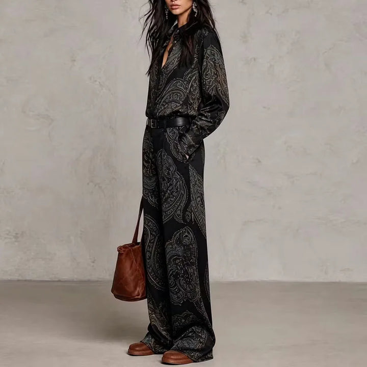 Side view of black paisley print two-piece shirt and wide leg pants set with belt