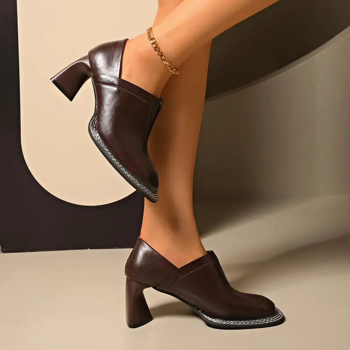 Side view of brown loafer with block heel worn on foot