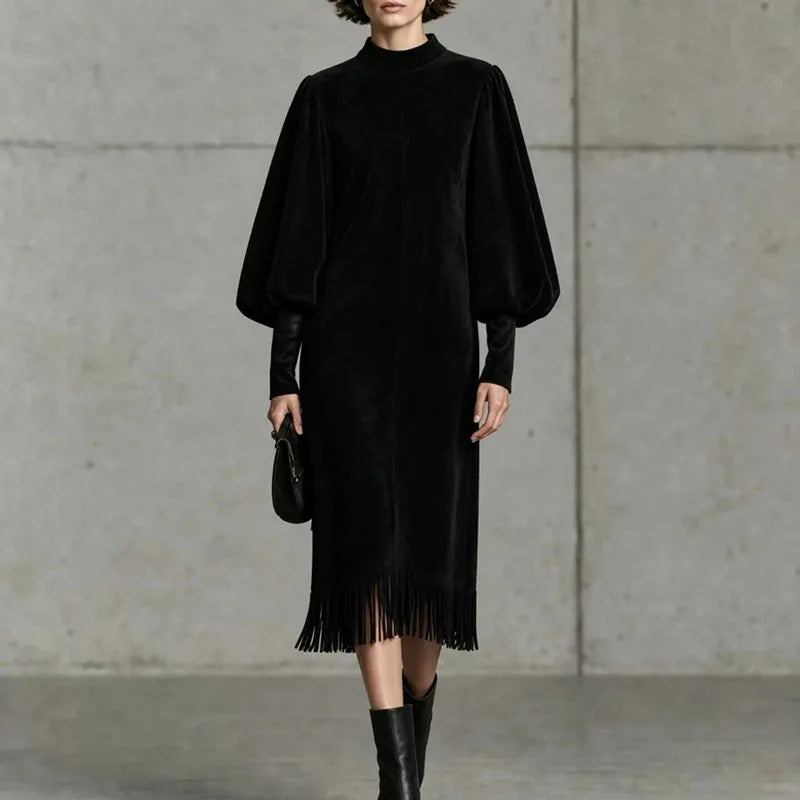 Woman wearing black velvet lantern sleeve dress with fringe hem, front view