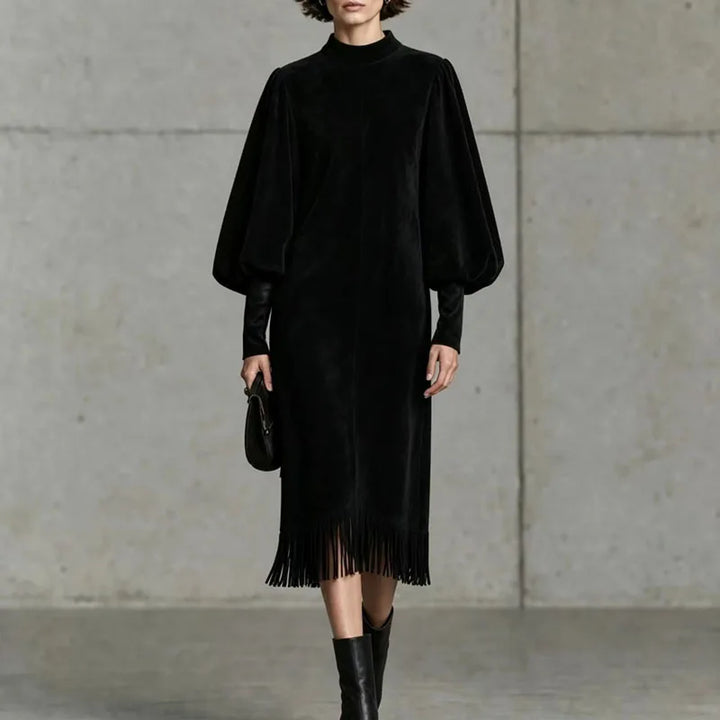 Woman wearing black velvet lantern sleeve dress with fringe hem, front view