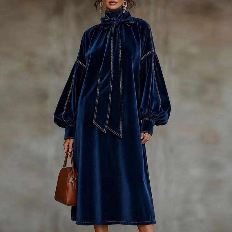 Woman wearing navy blue velvet maxi dress with bow tie neckline