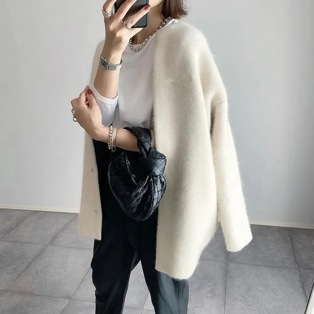 Off-white knit cardigan worn open with black trousers