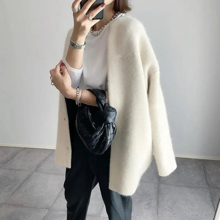 Off-white knit cardigan worn open with black trousers