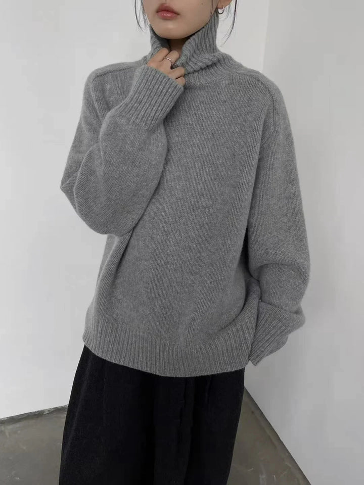 Woman wearing light gray turtleneck sweater with black pants