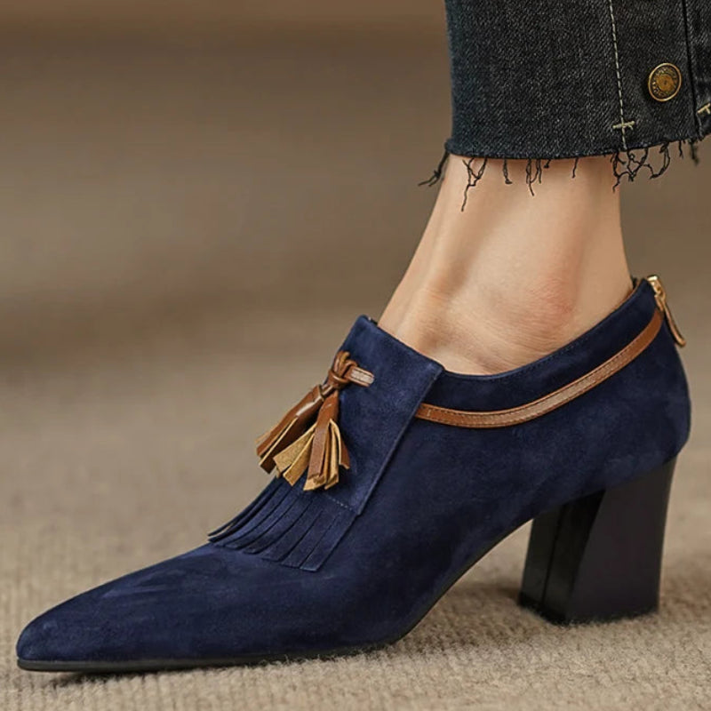 Close-up side view of navy suede pointed-toe pump with tassel detail