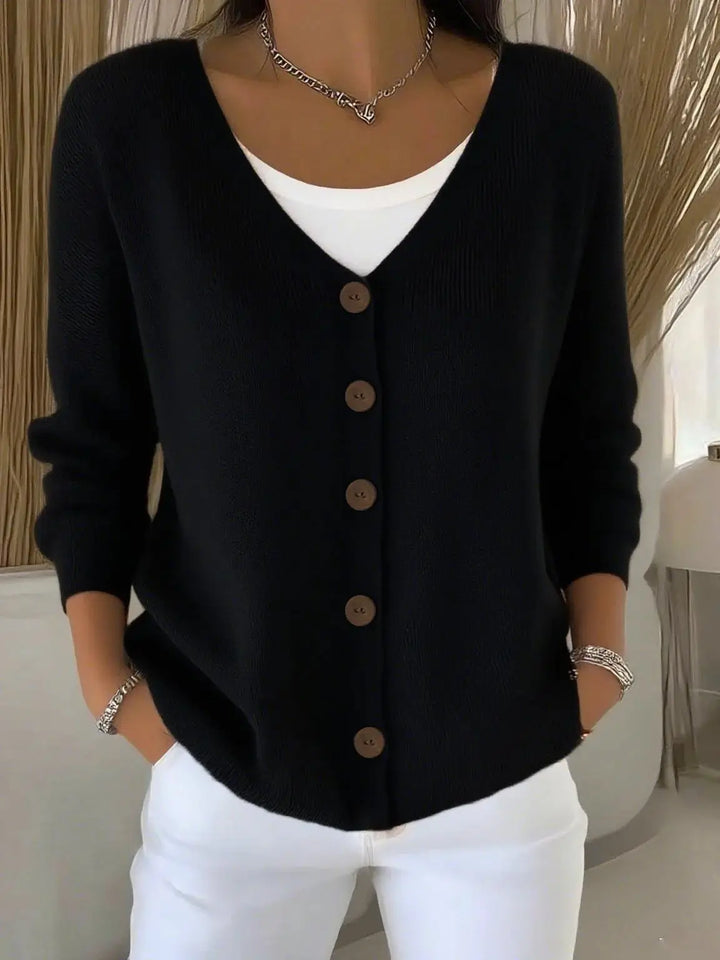 Woman wearing black button front knit cardigan over white top