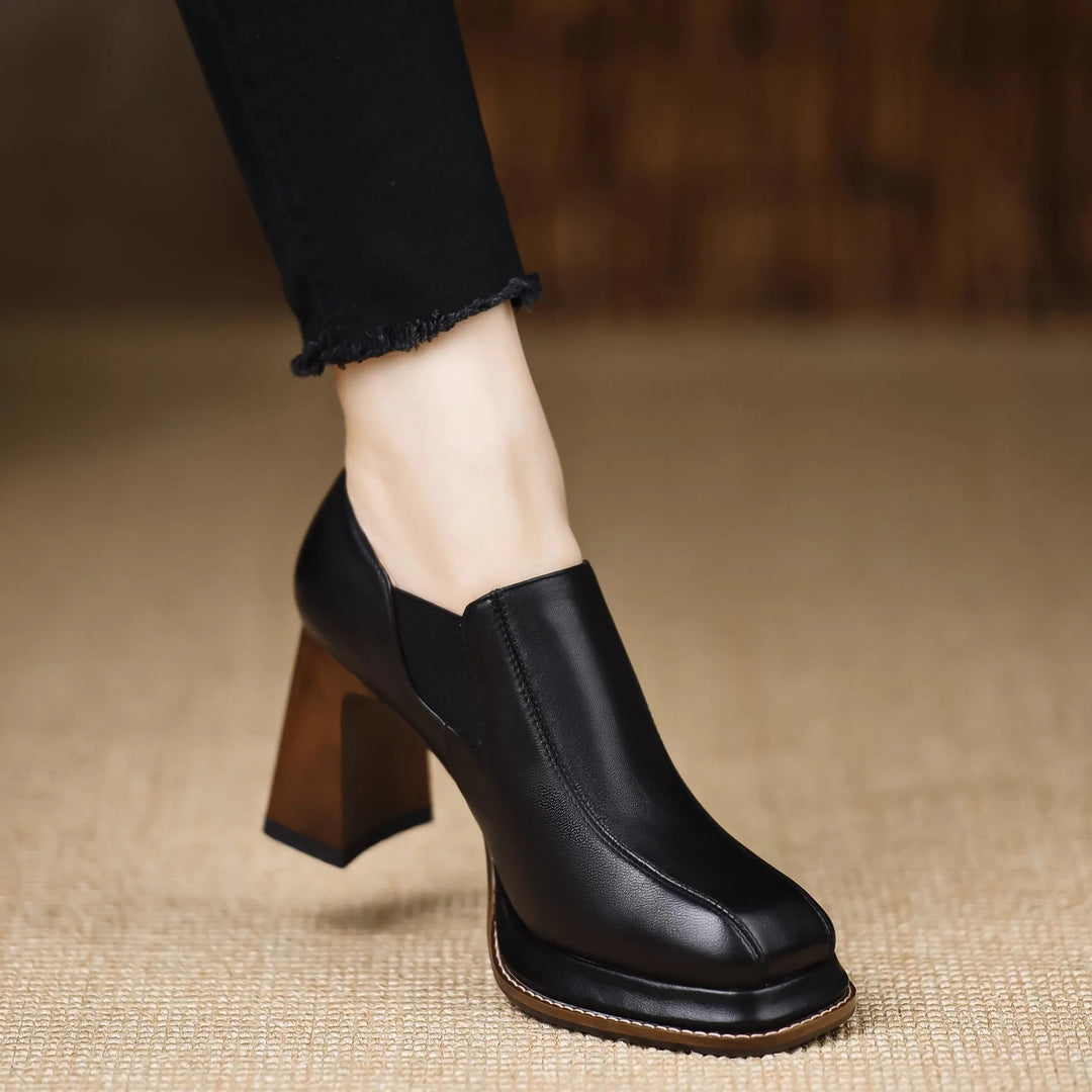 Close side view of black leather block heel pump