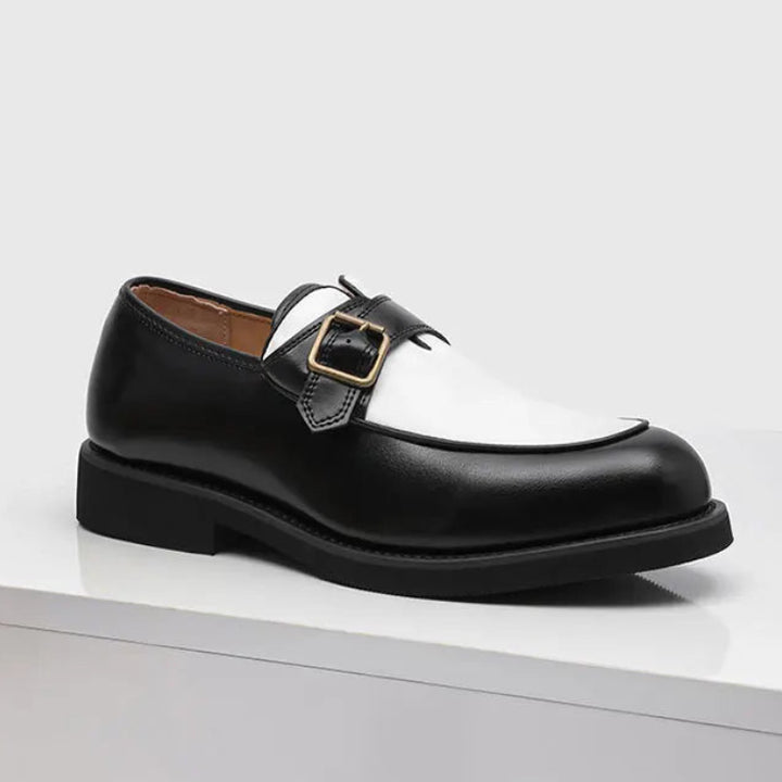 Black and white two-tone loafer side profile with buckle strap on white surface