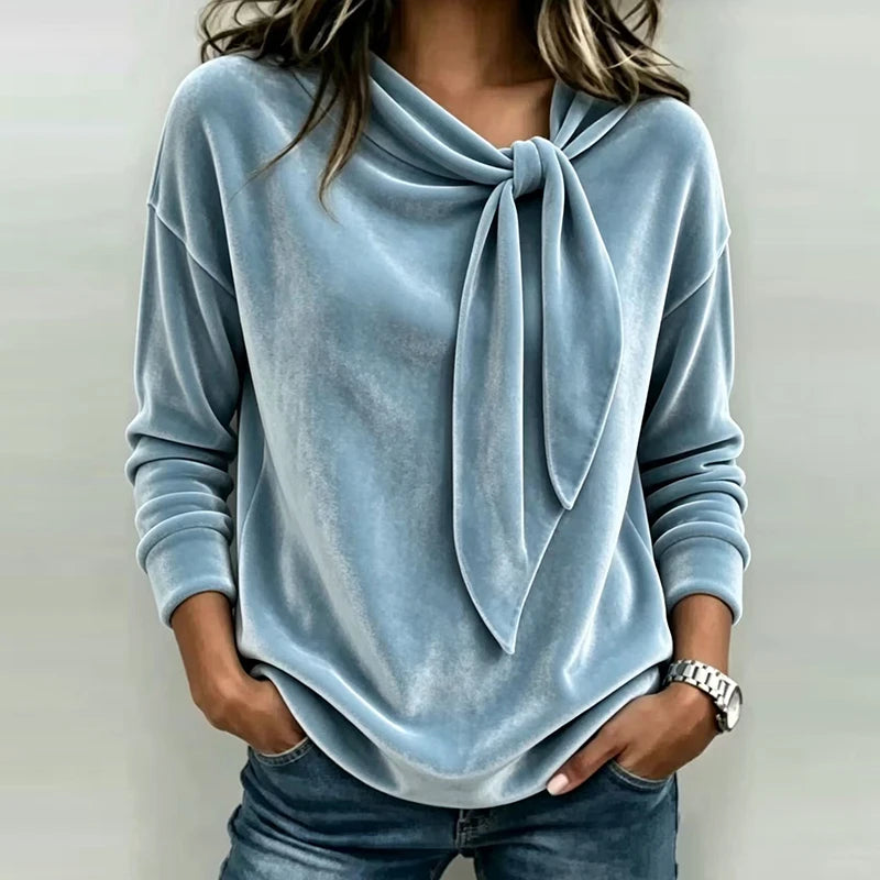 Woman wearing light blue velvet bow neck pullover top