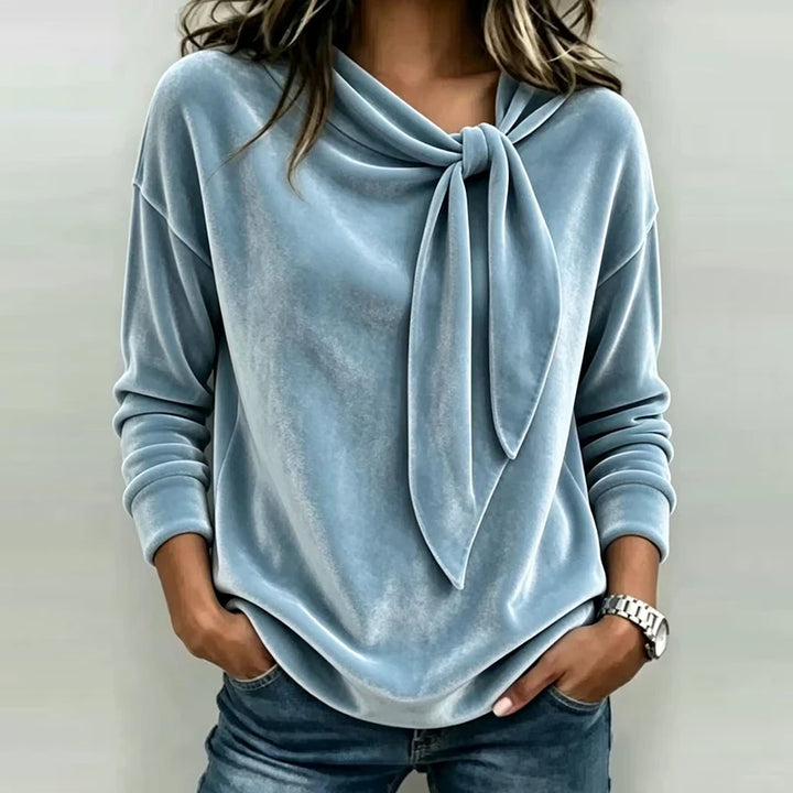Woman wearing light blue velvet bow neck pullover top
